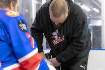 III divisioonan ottelu Huskit vs K-Ketut, Kempele (04.10.2025). Huskien huoltaja Markku Junnonaho vaihtaa joukkueen kapteenille Juho Mehtälälle uuden nauhan luistimeen edellisen katkettua kesken vaihdon.